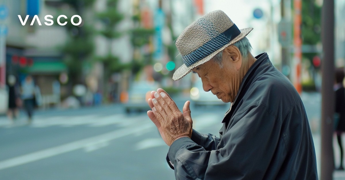 Un bărbat în vârstă care se înclină cu mâinile împreunate, reprezentând salutul în japoneză.