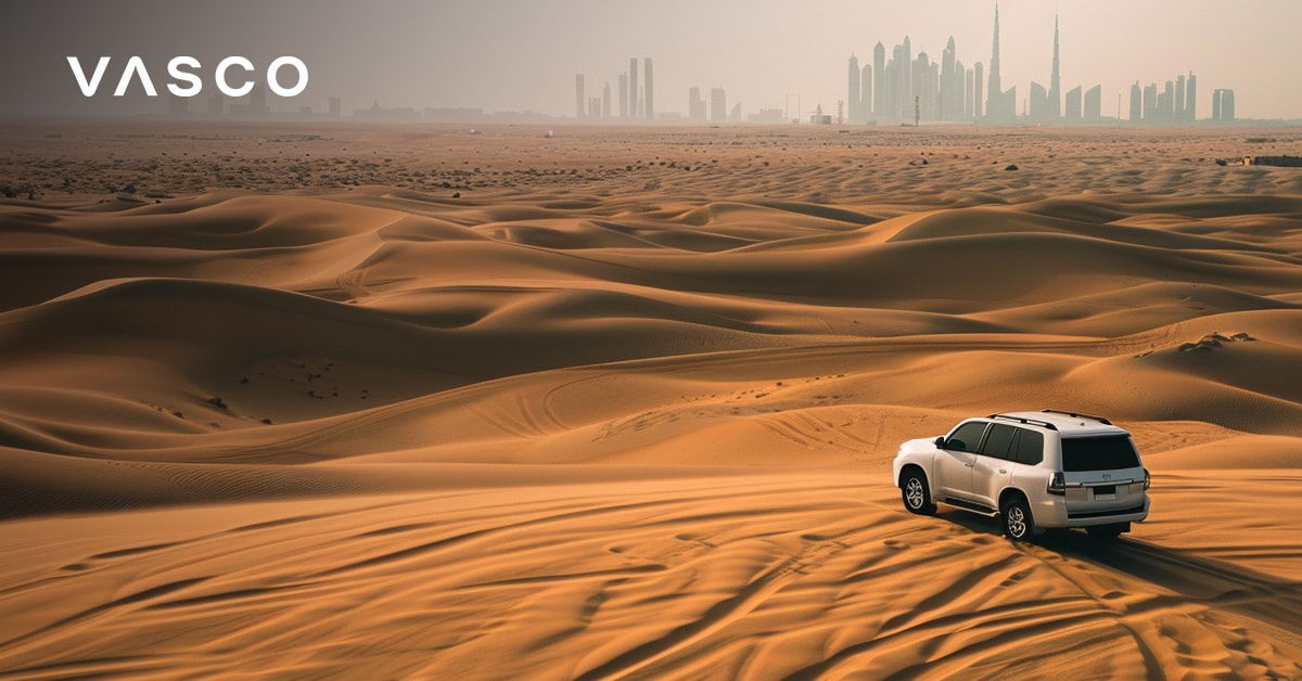 SUV care conduce prin deșertul Dubai cu orizontul orașului în depărtare.
