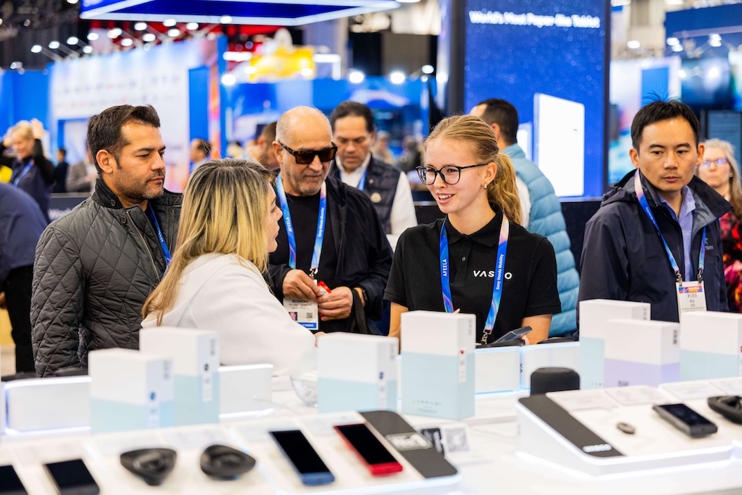 CES 2026 Un grup de oameni zâmbitori discută la standul Vasco Electronics din cadrul CES 2026.