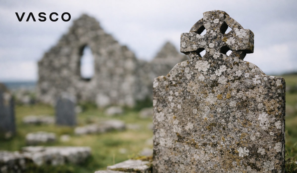 piatră funerară cu cruce celtică erodată lângă ruinele unei pietre antice