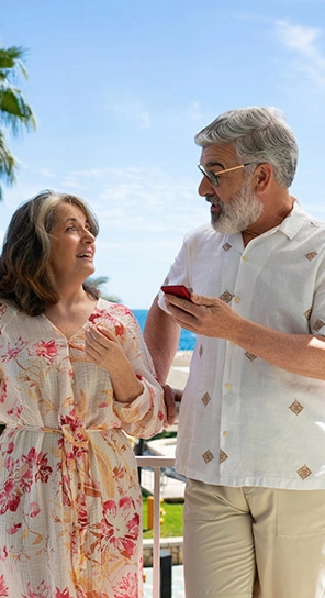 Două persoane în vârstă țin în mână dispozitive Vasco V4 și vorbesc între ele, prezentând cele cinci opțiuni diferite pentru viteza de redare.