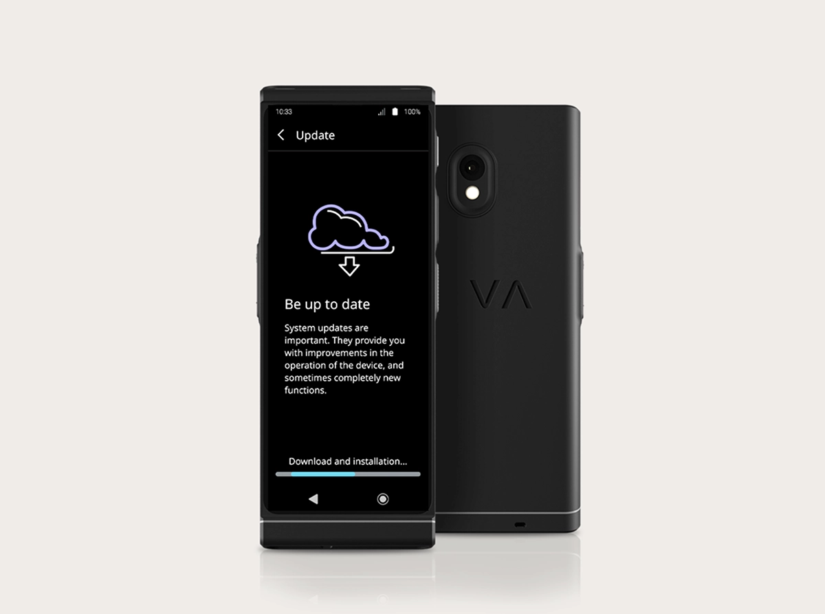 O fotografie de studio a produsului Vasco Translator V4, care prezintă interfața de actualizare a sistemului. Două dispozitive negre sunt așezate unul lângă altul: unul orientat cu fața spre cameră, iar celălalt cu spatele. Ecranul afișează o pictogramă în formă de nor cu o săgeată de descărcare, titlul „Fii la curent” și o bară de progres în partea de jos, cu textul „Descărcare și instalare...”. Vederea din spate prezintă camera cu două obiective și logo-ul „VA” în relief.