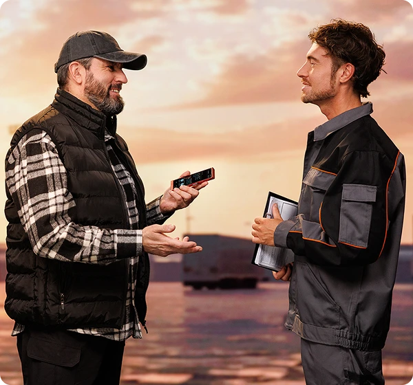 Doi bărbați discută între ei; șoferul de camion ține un Vasco Translator V4, în timp ce persoana din fața lui, un lucrător din depozit, ține mai multe documente. Aceștia comunică simplu și eficient cu ajutorul lui Vasco Translator.