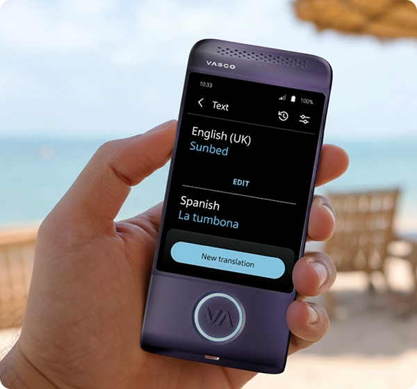 Un prim-plan al unei mâini care ține un dispozitiv electronic de traducere Vasco, de culoare violetă. Ecranul afișează traducerea unui text din engleză (Marea Britanie) în spaniolă, cuvântul „Sunbed” fiind tradus prin „La tumbona”. Fundalul este reprezentat de o scenă luminoasă, însorită, de pe plajă, cu o imagine estompată a oceanului, nisip auriu, câteva șezlonguri și o umbrelă de plajă din paie. 